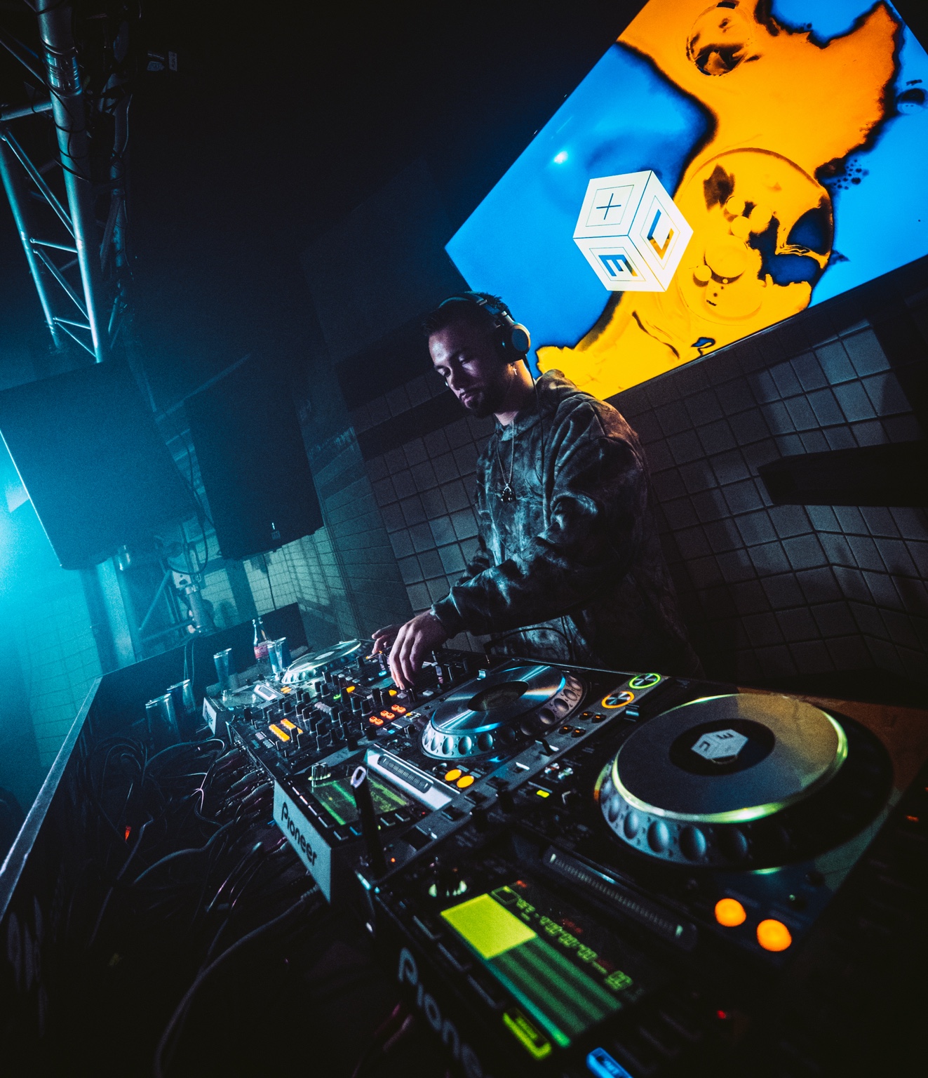AARON H mixing on Pioneer DJ decks under blue and orange stage lights