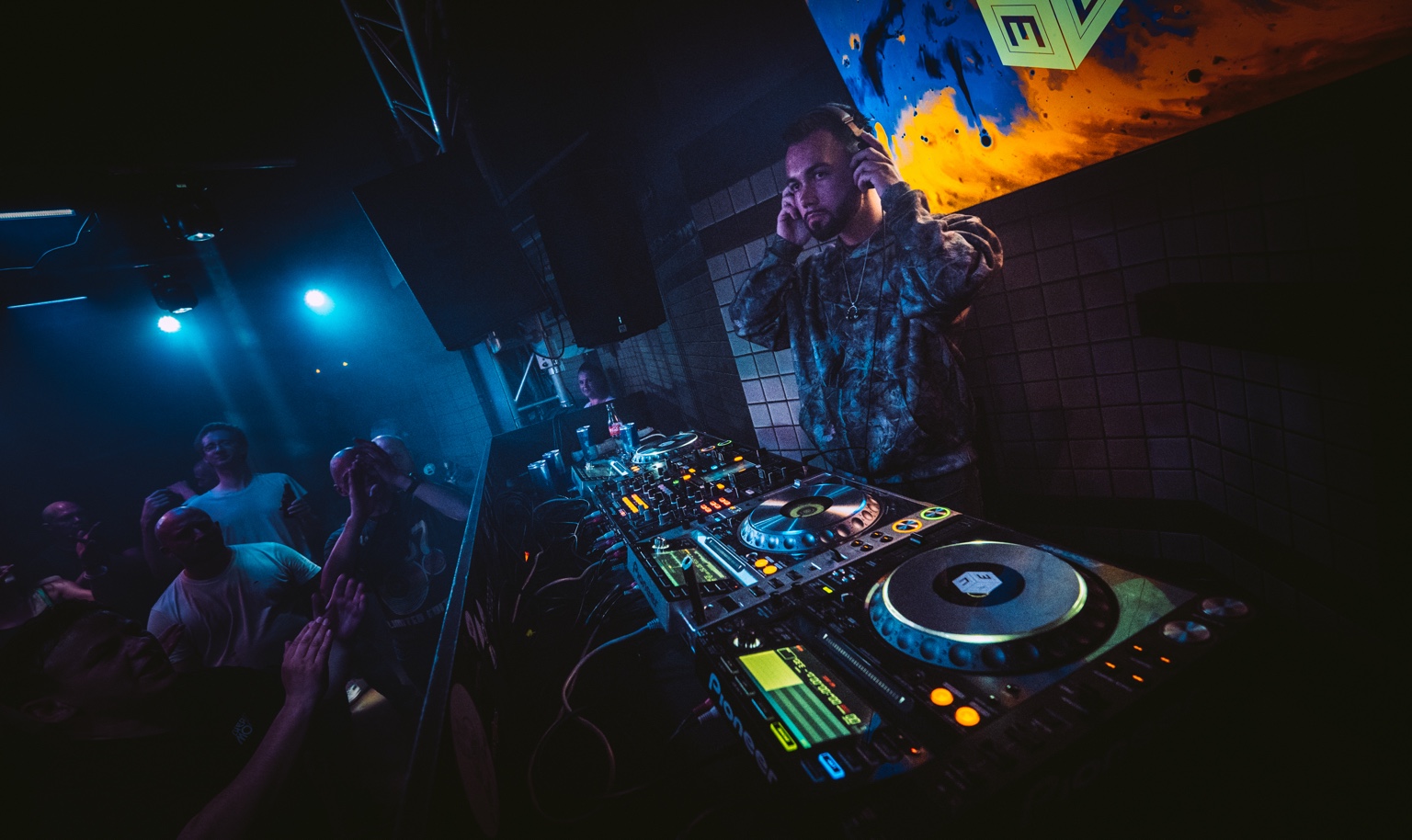 AARON H listening through his headphones with the audience beside the DJ booth